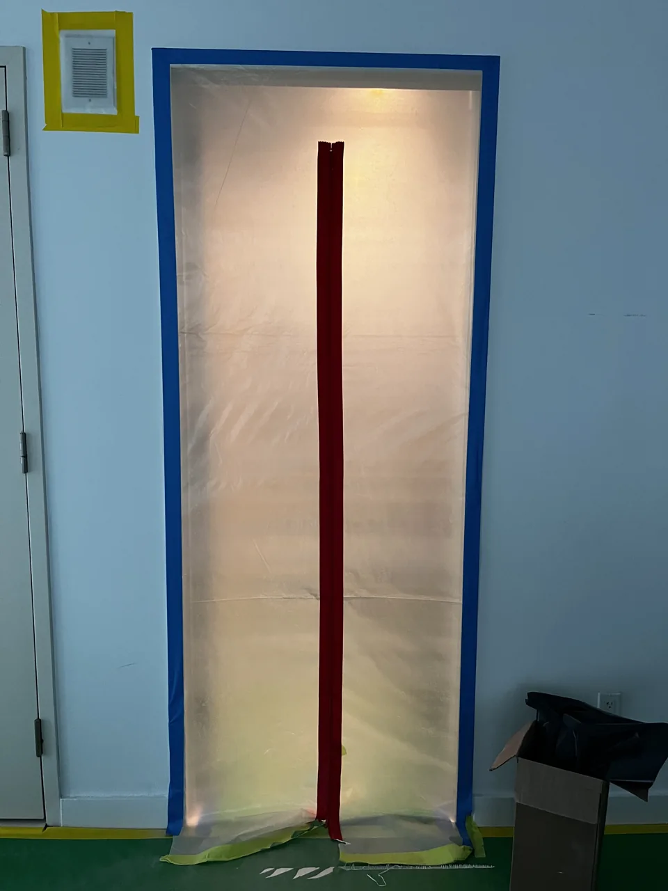 Plastic containment barrier with a red zippered entrance and floor protection on a GreenRoom job