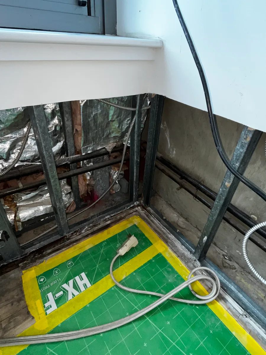 Opened lower wall cavities with metal framing and taped floor protection